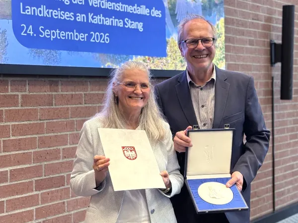 Katharina Stang zeigt ihre Urkunde und Jürgen Vogt zeigt die Verdienstmedaille des Landkreises Ludwigsburg
